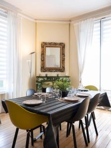 a dining room with a table with chairs and a mirror at Luxe Poincare in Nancy