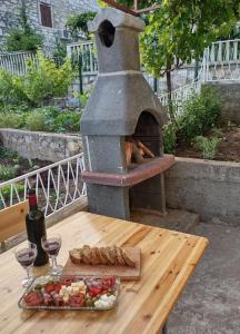 een buitenoven met eten en wijnglazen op een tafel bij Apartman Marine in Prvić Luka