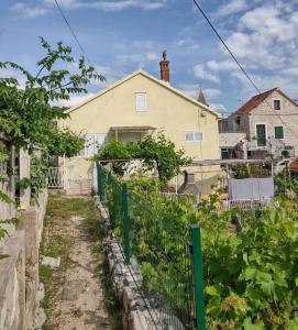 a fence in front of a house with a yard at Apartman Marine in Prvić Luka