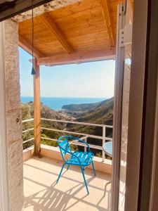 une chaise bleue sur un balcon avec vue sur l'océan dans l'établissement Sofia's Rooms, à Himarë