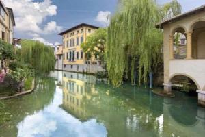 uma vista para um rio com edifícios e uma ponte em Elegance and comfort a due passi da SACILE CENTRO em Sacile