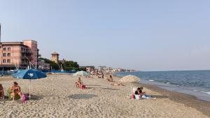 een groep mensen op een strand met parasols bij Karina, to the beach with terrace and private parking in Savona