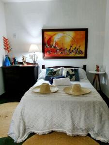 Un dormitorio con una cama con dos sombreros. en Andorinhas "Mini casa de hóspede" en Niterói