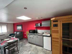 a kitchen with red walls and a table and a kitchen with a dining room at Un moment zen à Warhem in Warhem