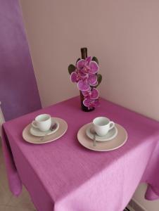 einem lila Tisch mit zwei Tassen und einer Vase Blumen in der Unterkunft Da Luigi locazioni brevi turistiche in Monopoli