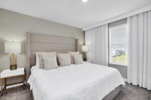 Un dormitorio blanco con una gran cama blanca y una ventana en Awesome Super Mario at Champion Gates, en Davenport