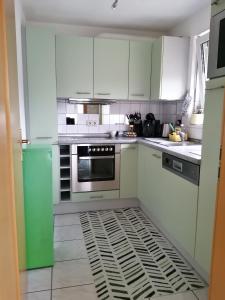 uma cozinha com armários brancos e um frigorífico verde em Schicke 2 Zimmer Wohnung nah an Stuttgart Messe Flughafen em Ostfildern