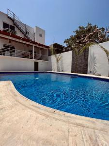 une grande piscine bleue en face d'un bâtiment dans l'établissement Residencia en el centro de Puerto Escondido, à Puerto Escondido