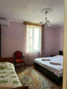 een slaapkamer met 2 bedden, een raam en een stoel bij Irina in Tskaltubo