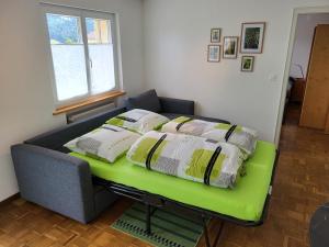 a bed with pillows on a green bench in a room at Les petits Rosiers in Tramelan