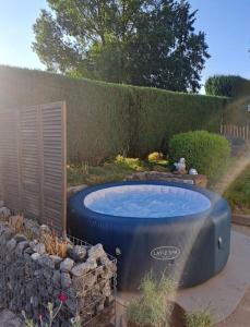 una bañera de hidromasaje en un jardín con una pared de piedra en Gîte 'Toi et moi ' en Graux