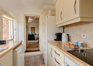 a kitchen with white cabinets and a plate of food on the counter at Skyes House in Southwold