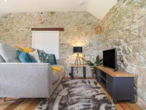 a living room with a couch and a stone wall at The Hayloft in Helston
