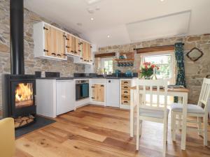 a kitchen with a fireplace and a table and chairs at The Hayloft in Helston
