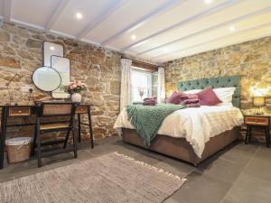 a bedroom with a bed and a stone wall at The Hayloft in Helston