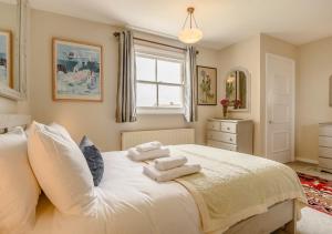 a bedroom with a white bed with towels on it at 10B South Green in Southwold