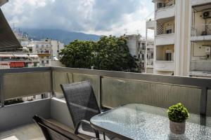 a glass table and a chair on a balcony at Silver Central Apartment in Volos