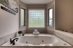 a large white tub in a bathroom with two windows at Love View in Sevierville