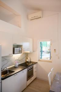 a kitchen with white cabinets and a sink and a window at Holiday Home Laumar in Klek