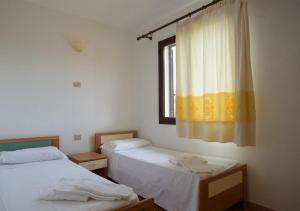 蒙特佩特羅素的住宿－Residence Agrifoglio，客房设有两张床和一个带窗帘的窗户。