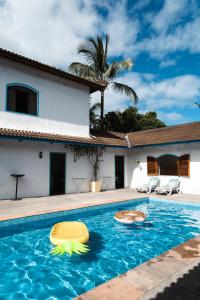een huis met een zwembad met twee speeltjes erin bij Villa Salgada Maresias in Maresias