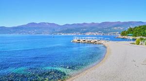 a beach with blue water and a rocky shore at Apartman Lana in Rijeka