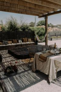 a patio with two tables and a couch at Hippie house בית היפי in Mitzpe Ramon