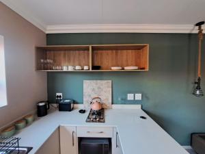 una cucina con bancone bianco e pareti verdi di Greenhouse a Boksburg
