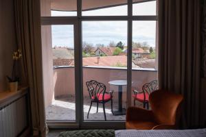 Zimmer mit Blick auf einen Balkon mit Stühlen und einem Tisch in der Unterkunft HOTEL GRACIAN in Sremska Mitrovica