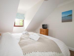 a bedroom with a white bed with towels on it at The Dunes in Crantock