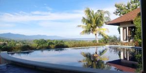 einen Swimmingpool mit Palmen und ein Haus in der Unterkunft The Dharma Araminth Villa - Lovina Mountain and Sea View in Lovina