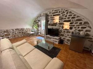 ein Wohnzimmer mit einem Sofa und einer Steinmauer in der Unterkunft Hôtel Mas de l'Espaïre in Les Vans