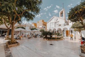 una piazza cittadina con persone sedute ai tavoli e una torre dell'orologio di Apartamento Salinas a Fuengirola