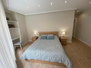 um quarto com uma cama, 2 candeeiros e uma cadeira em Apartamento La Duna de Gamazo en Santander em Santander