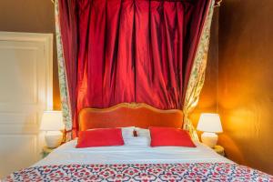 a bed with a red curtain and two red pillows at Les Jardins Haute Couture in Huismes