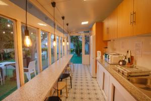 a kitchen with a counter with a sink and some chairs at Hostel das Flores in Senhora da Hora