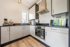 a kitchen with white cabinets and black counter tops at Ashview 8 - Heathrow - Business - Free Parking in Staines upon Thames