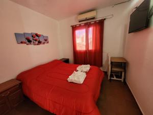 1 dormitorio con cama roja y cortina roja en Hotel Belgrano, en Villa Carlos Paz