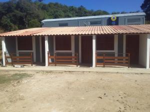 three benches in front of a building with a roof at Pousada Kart Clube in São João del Rei