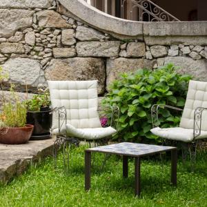 two chairs and a table in front of a stone wall at Casa do Conto - Arts & Residence in Porto