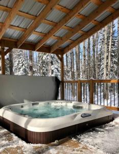 a hot tub on a deck with a wooden roof at Le Vaillant du Massif in Petite-Rivière-Saint-François