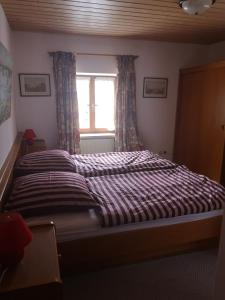 ein großes Bett in einem Schlafzimmer mit Fenster in der Unterkunft Gasthof Mühlegger in Wildsteig