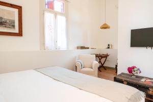 a white bedroom with a bed and a chair at Chalet Ficalho in Cascais