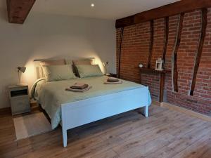 1 dormitorio con cama y pared de ladrillo en Le Bois d'Albran en La Calotterie