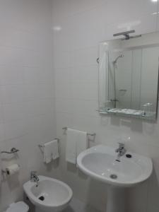 een witte badkamer met een wastafel en een spiegel bij Hotel Sinagoga in Tomar