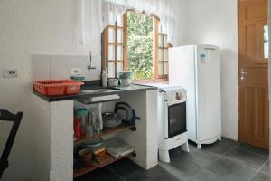 a kitchen with a white refrigerator and a sink at Villa Salgada Maresias in Maresias