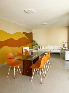 a dining room with a table and orange chairs at Casa de praia no Flamengo in Salvador