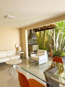 sala de estar con muebles blancos y mesa de cristal en Casa de praia no Flamengo en Salvador