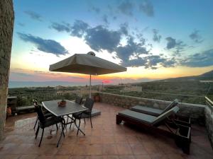 a patio with a table and chairs and an umbrella at Elaionas Apartments 2 in Riglia