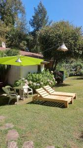 un patio con bancos, una mesa y una sombrilla en Villa la Candelaria en Sierra de los Padres